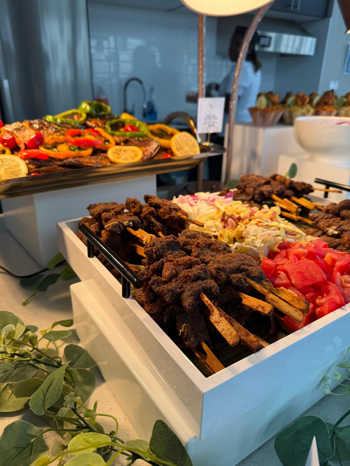Suya skewers and grilled fish catering station at a White Oats event